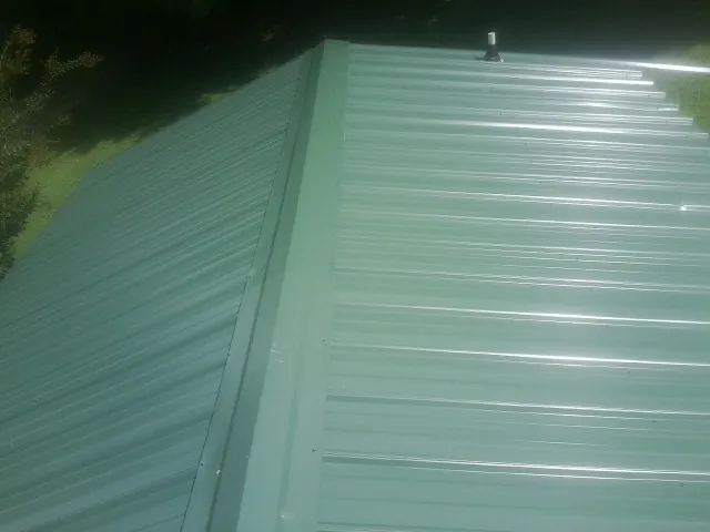 New green metal panels meeting at the ridge of a roof — Flat Roof Repair work by our crew in Sycamore