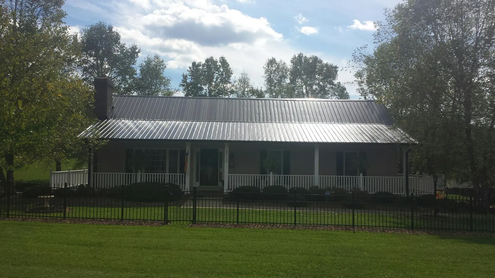Gray metal roof on a brick ranch with a full width front porch in Sycamore