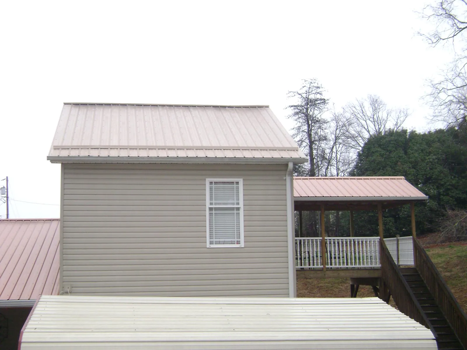 Tan metal roofs on a two story addition and attached porch, from a Roof Replacement job in Sycamore